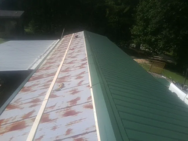 Old rusted panels beside newly installed green metal roofing — Wind Damage Roof Repair by Roofing Brothers in Stoneham