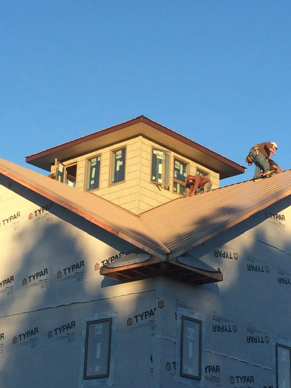 Roofers working around a rooftop cupola on a new metal roof at sunset — Roof Waterproofing in Stoneham by Roofing Brothers